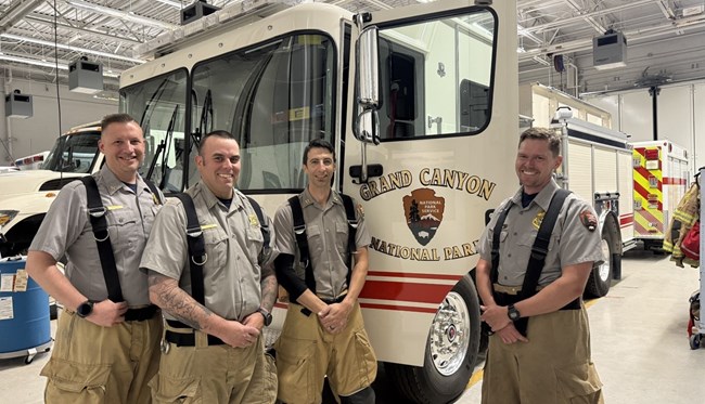 Structural Fire crew at Grand Canyon National Park Four men smile in front of a fire engine in an engine bay.