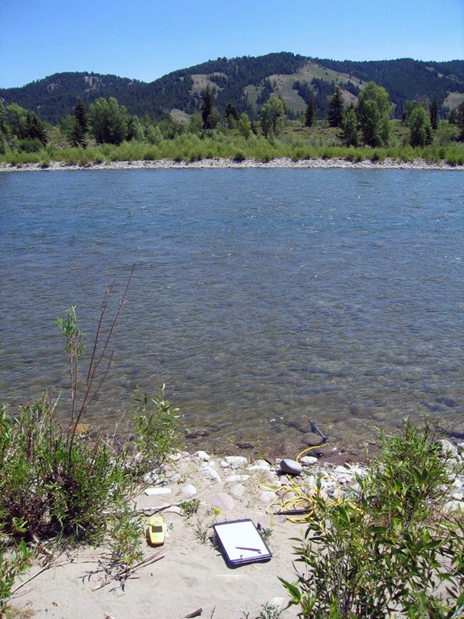 View across a river from a bank with water monitoring equipment