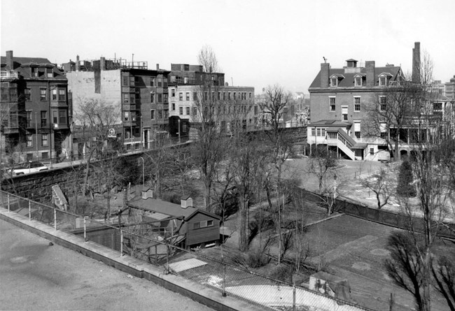 A black and white photo from above of the Navy Yard being separated from the surrounding city with the granite wall, cutting horizontally through the center of the image.