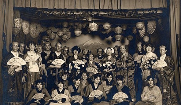 Black and white photo of men and women on stage for a performance.