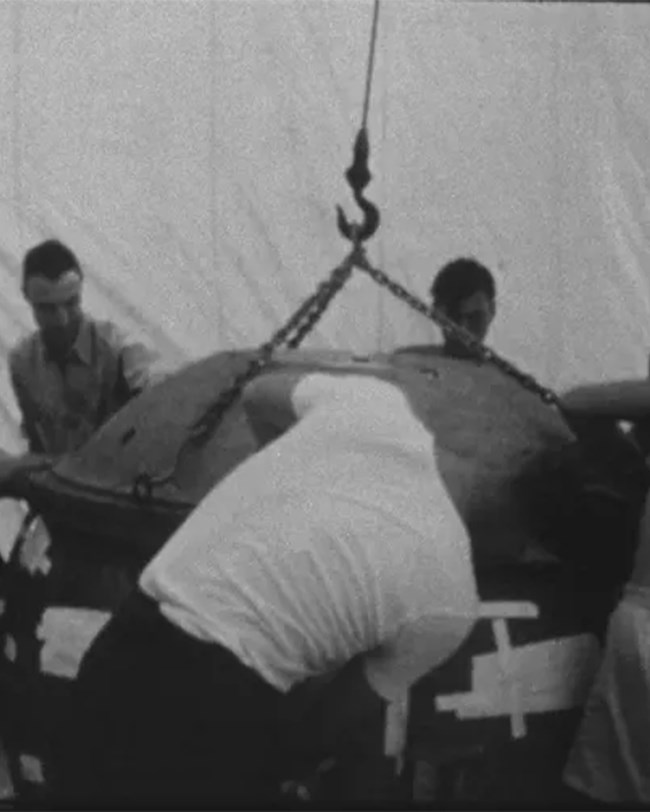 Several men gathered around a large metal sphere.