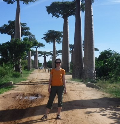 Sarah Gaines woman stands on a dirt road with palm trees on either side
