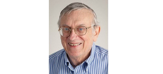 Headshot of man with glasses in light blue shirt