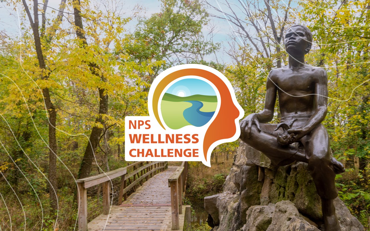 Bronze statue of young George Washington Carver holding a plant and a foot bridge in the background.