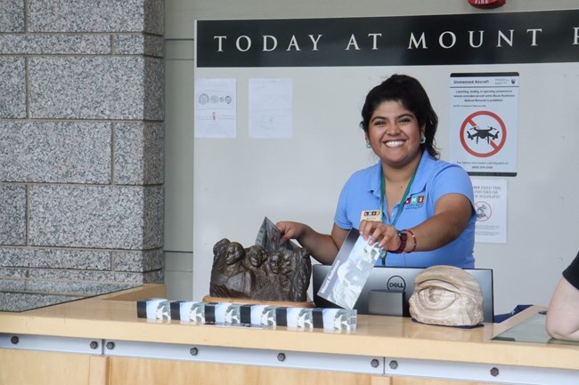 Gia working at the visitor center A woman hands out park maps to visitors