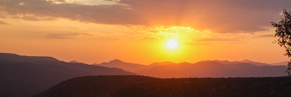A streaking orange sunset over silhouetted mountains.