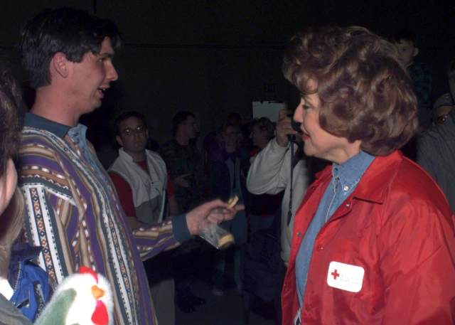 Gary Godorou, a flood victim of Grand Forks, North Dakota, thanks Red Cross President Elizabeth Dole for the efforts of the Red Cross during her visit to Grand Forks, AFB. April 23, 1997. A man wearing a colorful sweater talks to a woman wearing a red cross jacket.