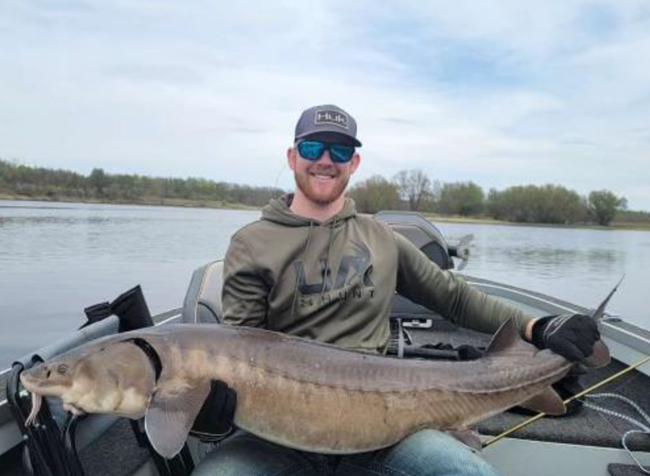 Grant Haley Photograph of person in a boat holding a large fish.