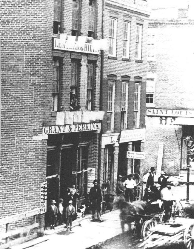 Grant Perkin leather store in Galena, Illinois black and white photo of tall brick building with people standing by doorway
