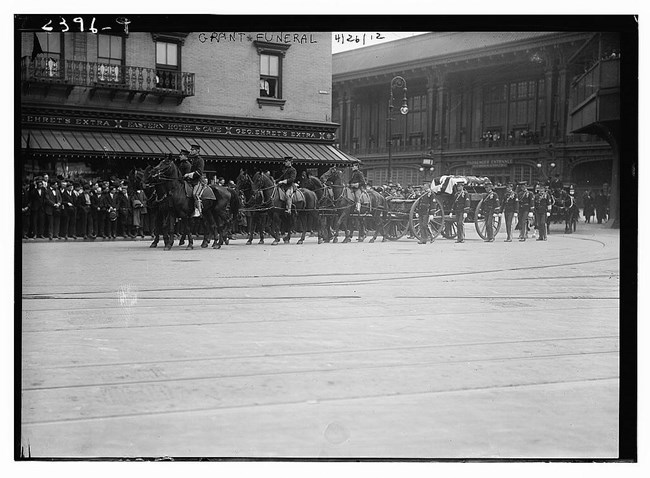 General Grant Funeral, LOC Black and white photo of horses with men on them pulling a dark carriage along a street with people in the background curb watching
