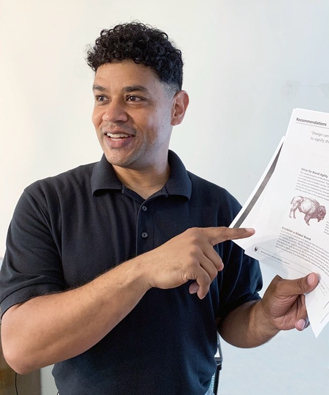Greg Aylsworth pointing to a paper with text and an image of a bison