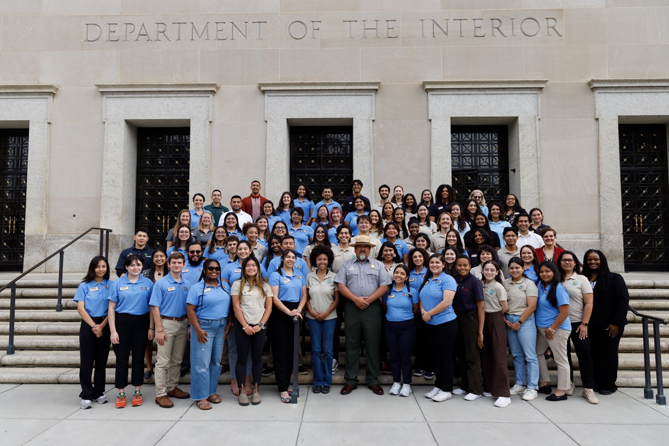 Group shot of LHIP-Mosaics Conference Group of individuals standing on steps in front of the U.S. Deartment of the Interior Building