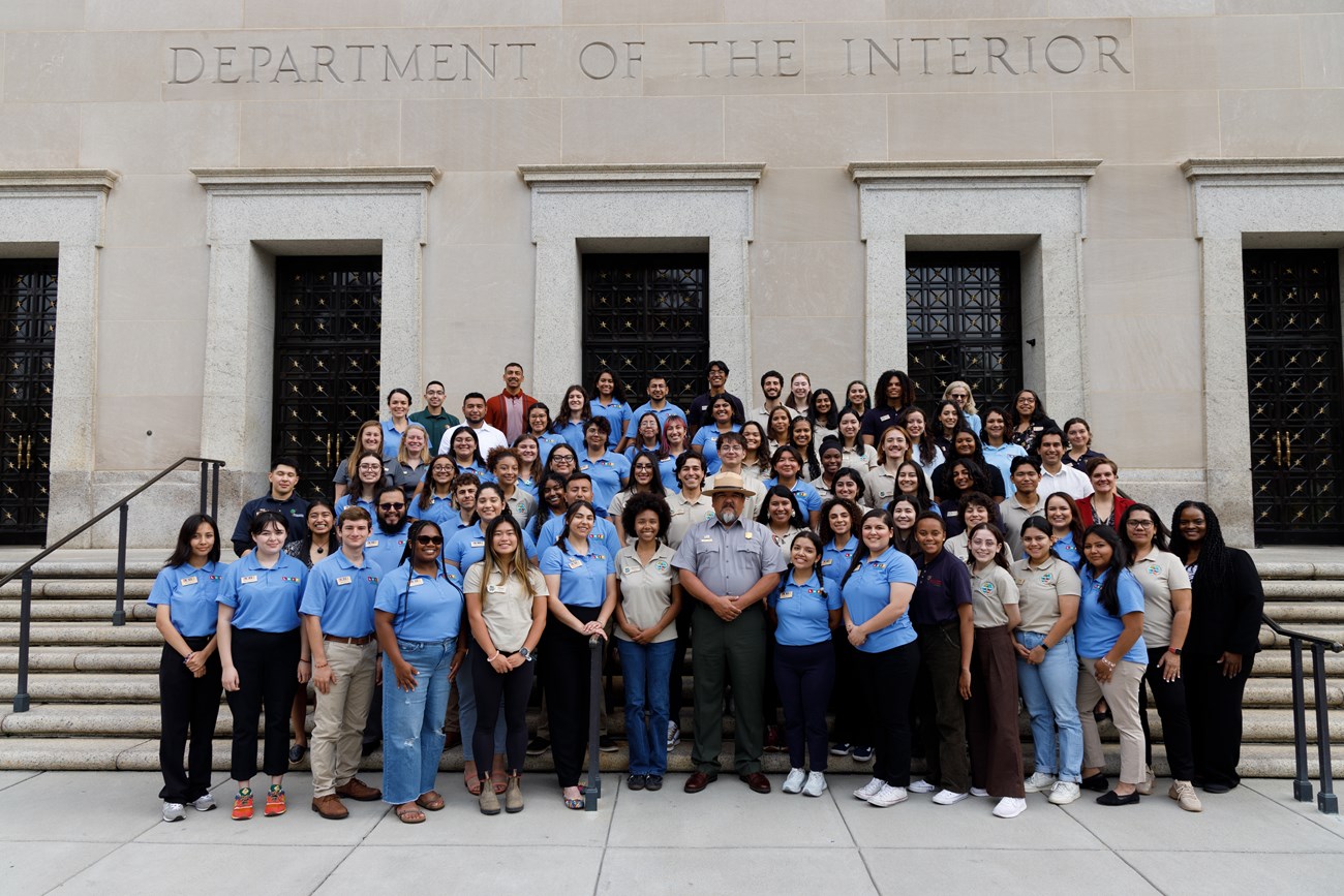 Group of individuals standing on steps in front of the U.S. Deartment of the Interior Building