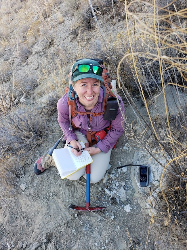 a person kneeling down at a fossil site