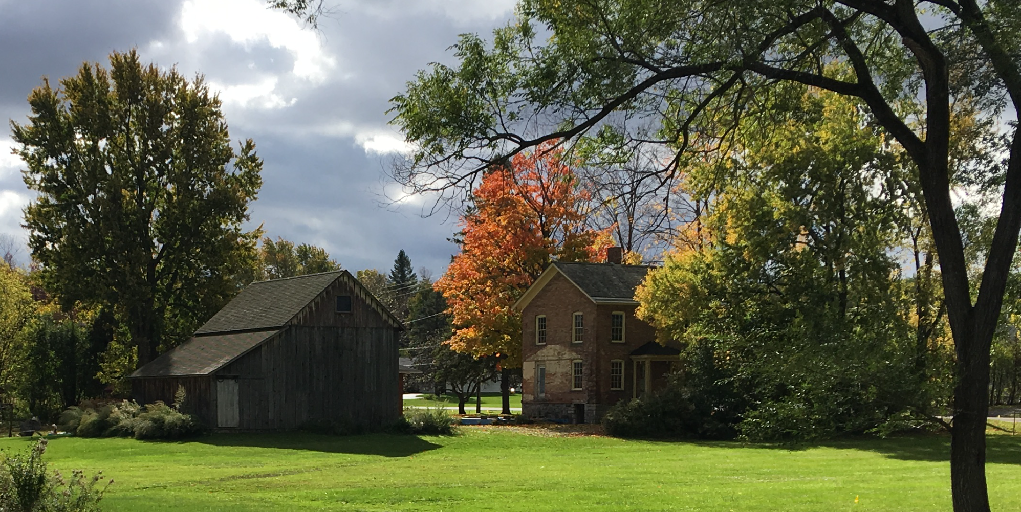 Small barn and a two-story brick house on a big lawn