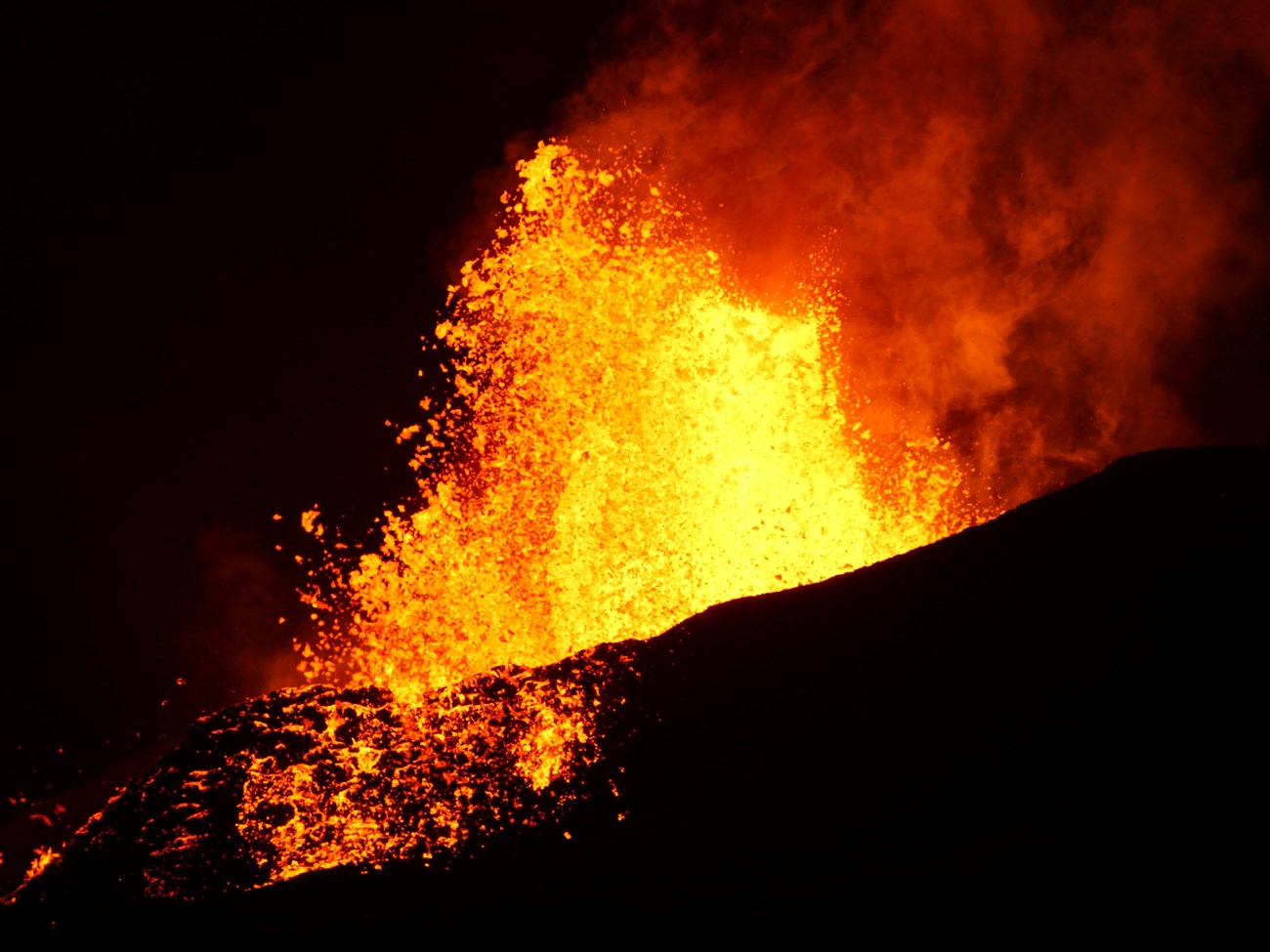 volcanic eruption with molten lava erupting into a dark night sky