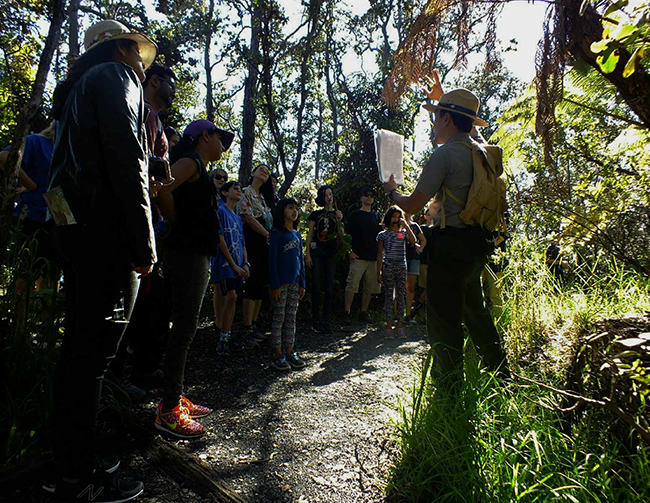 Ranger program into Kīlauea Iki crater. Ranger showing a graphic to visitors on a ranger program.