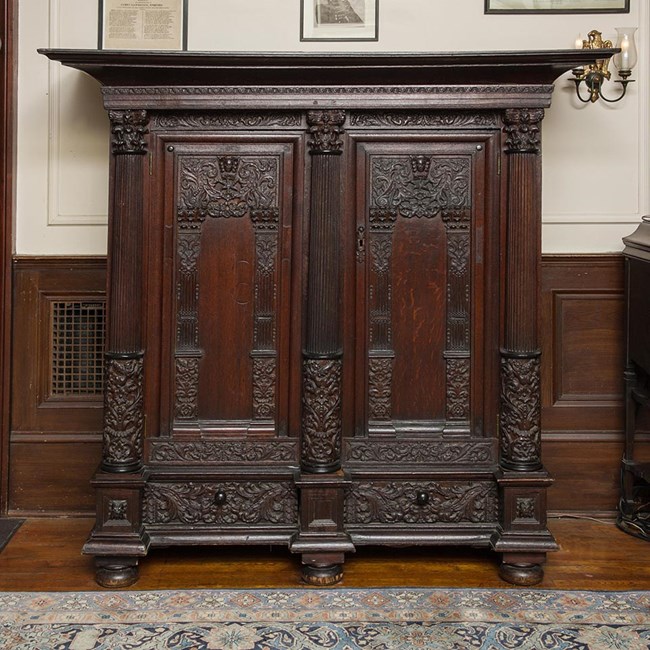 A carved wood cupboard with double doors.