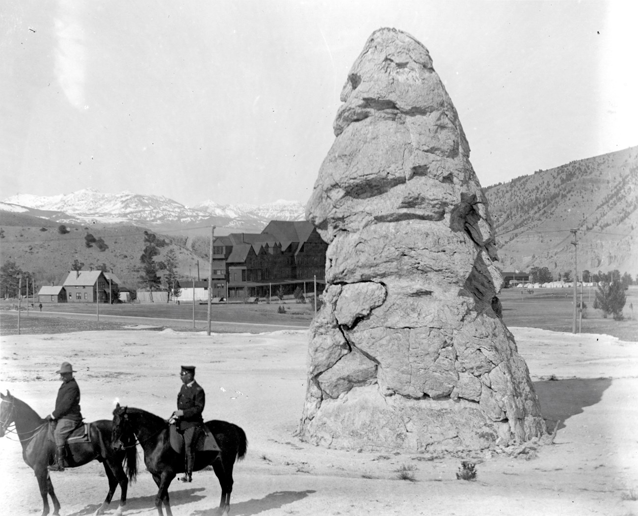 Two men on horseback in front of a tall rock cone