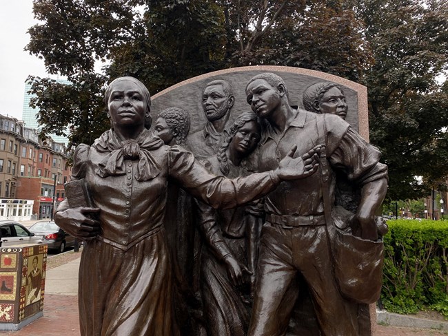 Harriet Tubman Memorial Step on Board of her guiding a group of people.