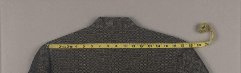 Demonstrating how to measure the shoulder width of a jacket.