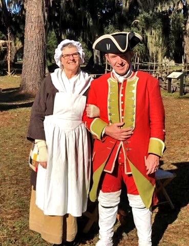 Photo of Tom and Karen Hartley wearing period costumes standing outside and smiling.