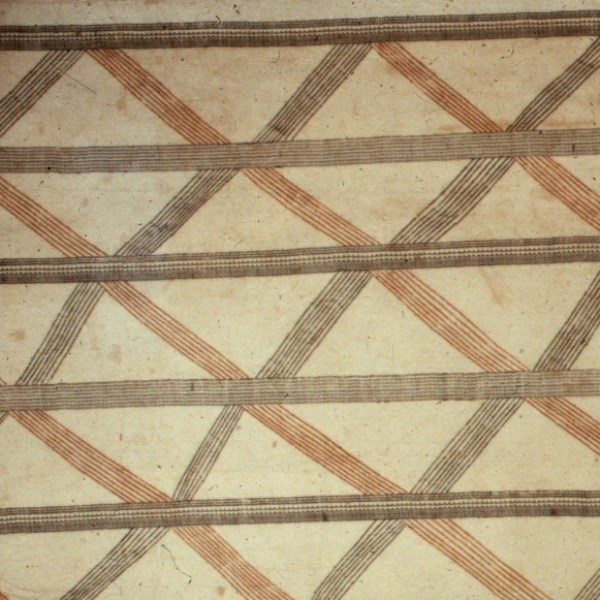 A closeup of traditional Hawaiian Kapa Barkcloth Brown cloth with red and black geometric lines in shape of diamonds
