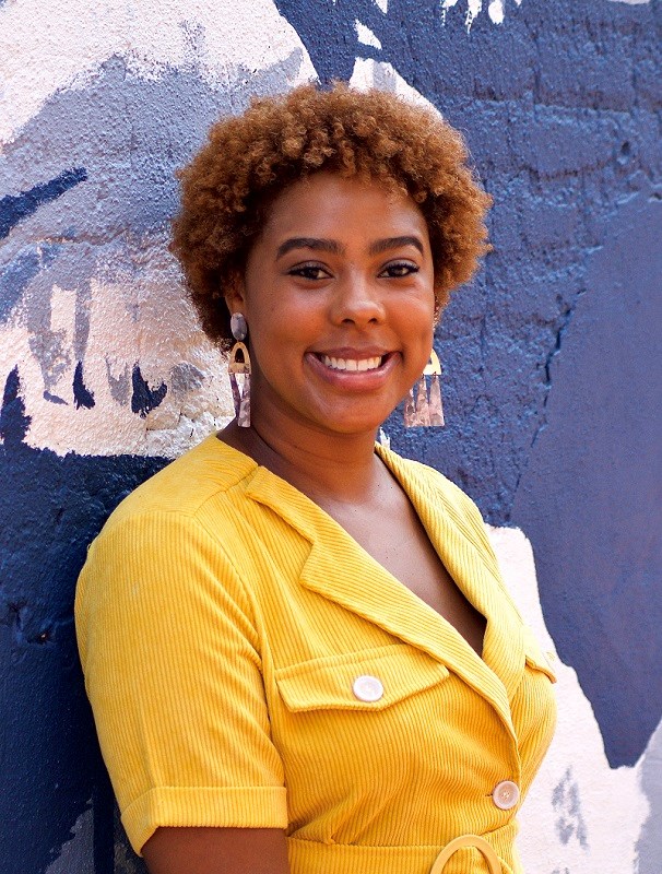 Subria Spencer Headshot headshot of a smiling Subria wearing a yellow bottom up shirt