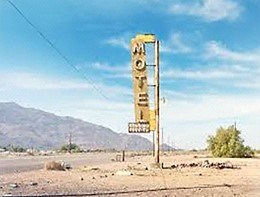 Yellow motel sign on a road in the desert.