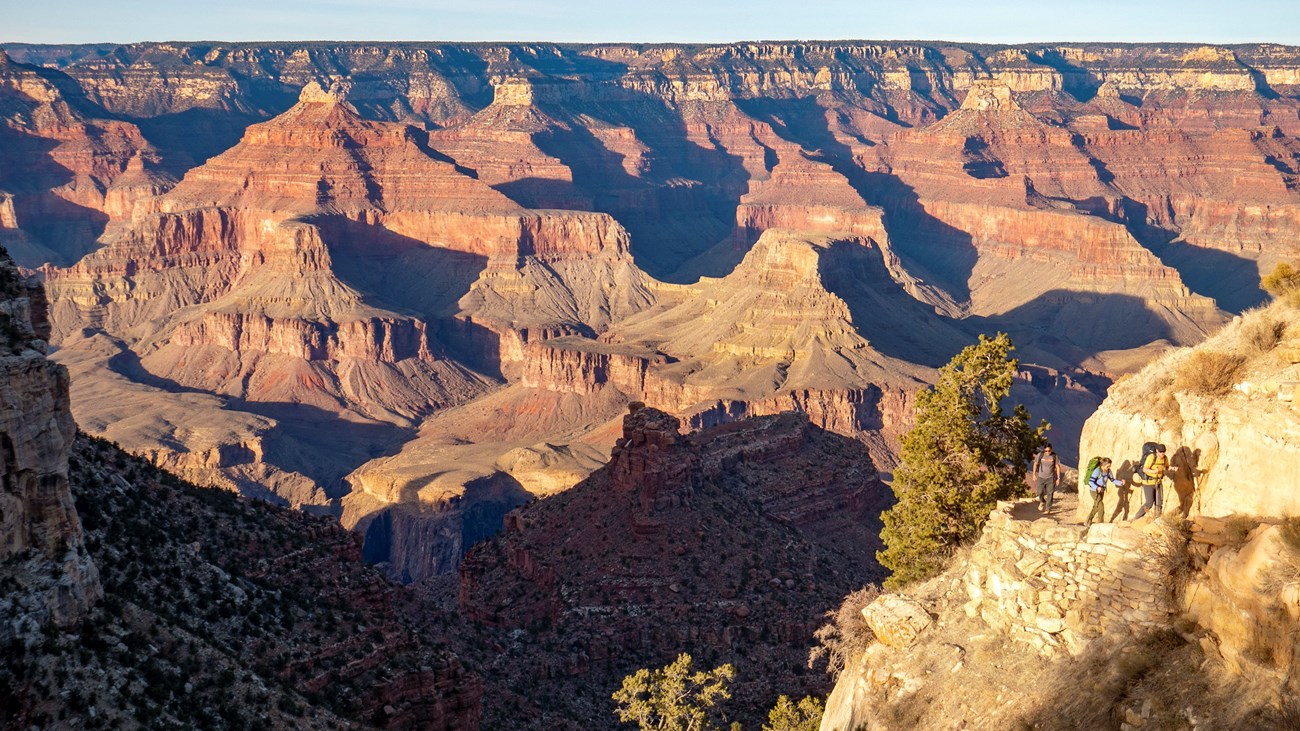 A small group of hikers ascend Bright Angel trail with a vast and colorful canyon as their backdrop. NPS Photo/M. Quinn