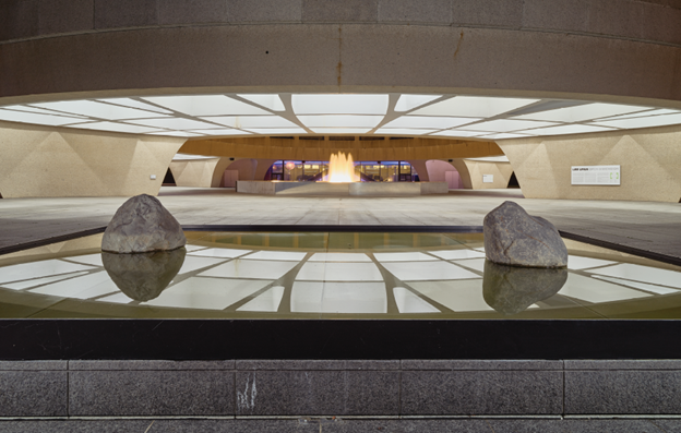 Hirshhorn Museum WA A wide horizontal open-air courtyard with a water fountain with stones and reflecting overhead light panels.
