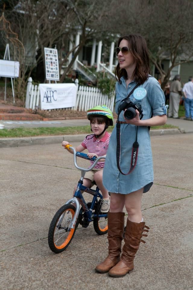 Historic House Fair 2013 Historic House Fair 2013: A mother with a helmeted child on a bike riding down a festive street.