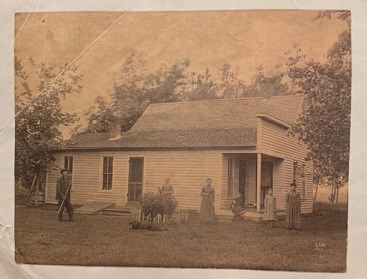 The Hopper Family standing outside of their homestead in 1880.