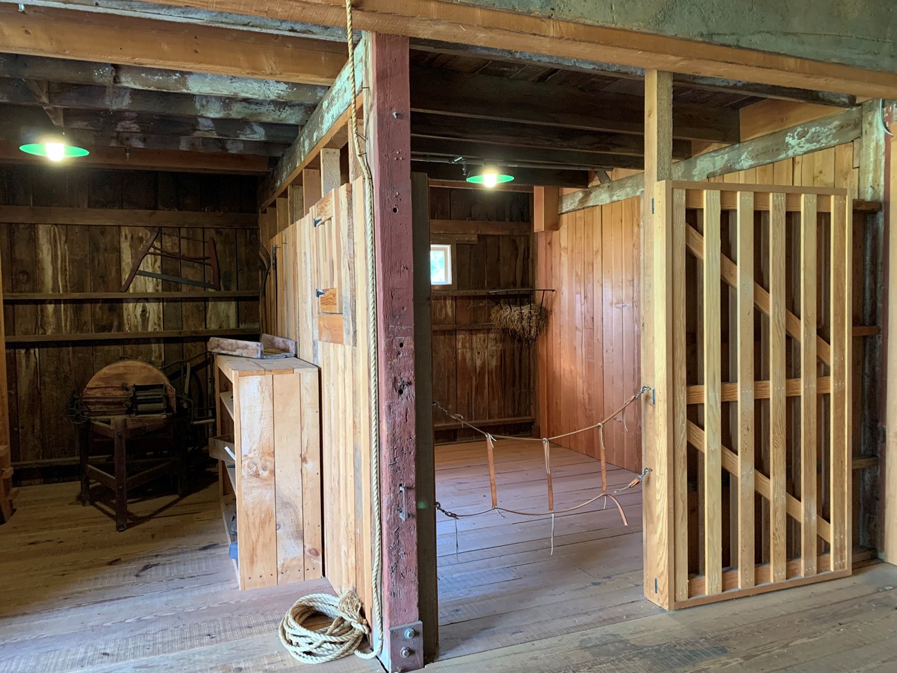 Horse Stall Two rooms inside a stable. The left room has a pitchfork and corn shucker. The right room is an empty stall for a horse.