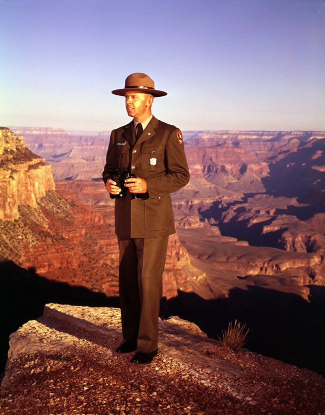 Howard Chapman in his uniform standing on the rim of the Grand Canyon.