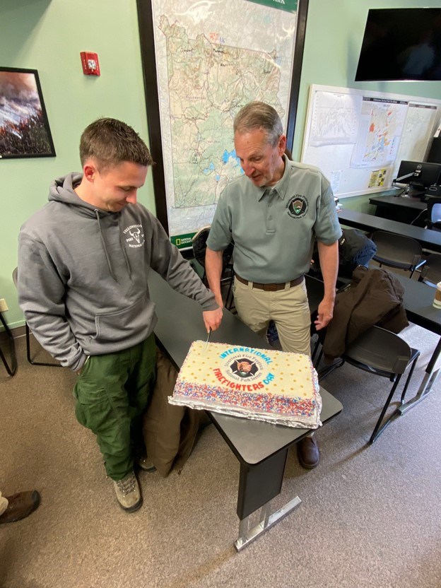 Celebrating International Firefighters' Day Two men hold a knife to cut a decorated cake for International Firefighters' Day.