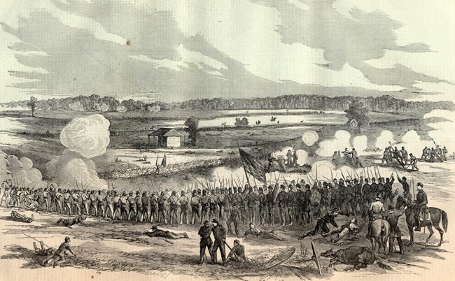 Open fields with soldiers and cannons in line of battle fighting with a distant opposing line, with wounded soldiers in the foreground.
