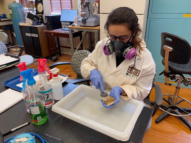 Research Associate cleans surrogate stone sample with a surface washing agent and agitation using a dish washing bristle brush.