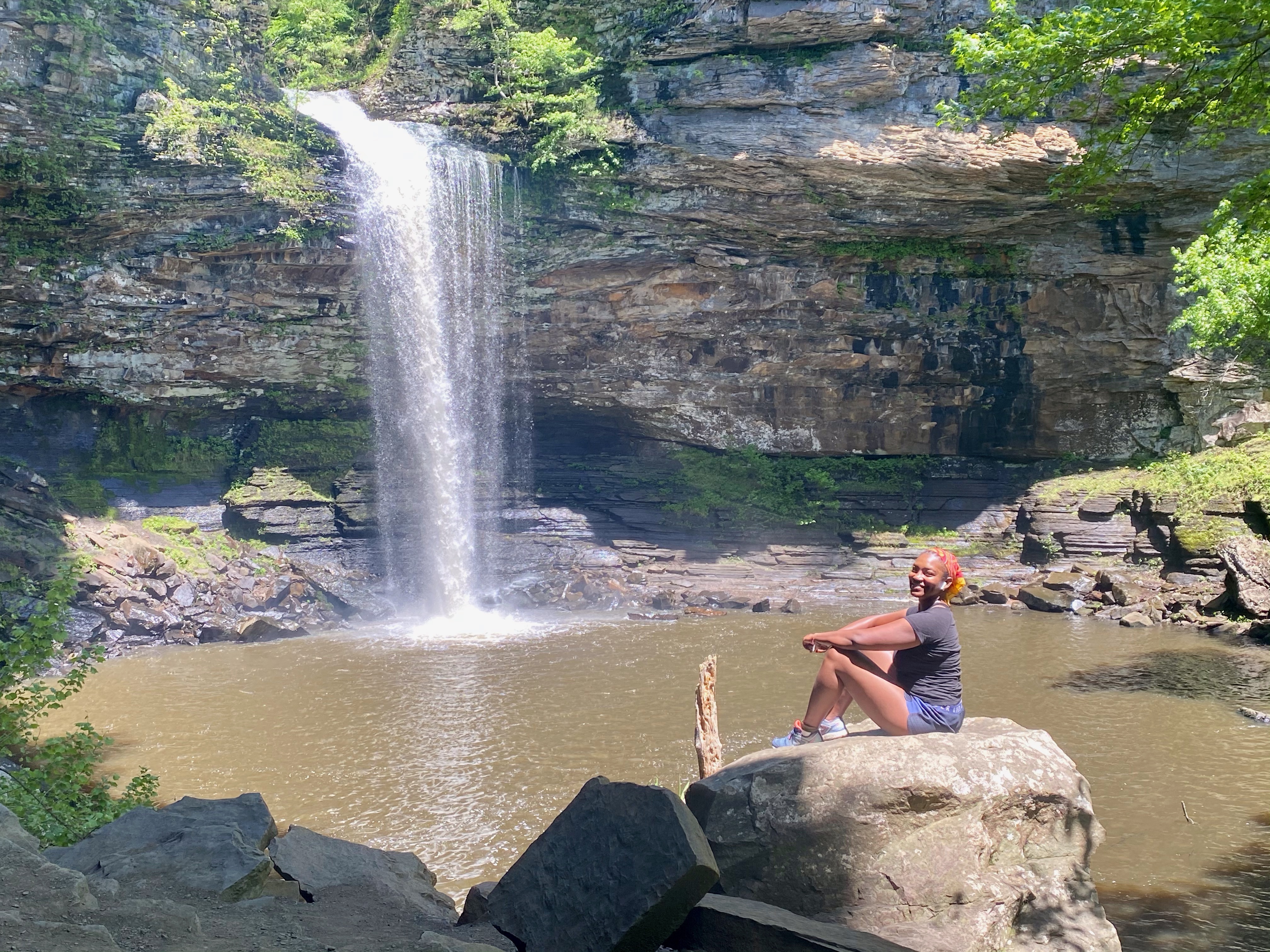 a young woman sitting in front of a waterfall