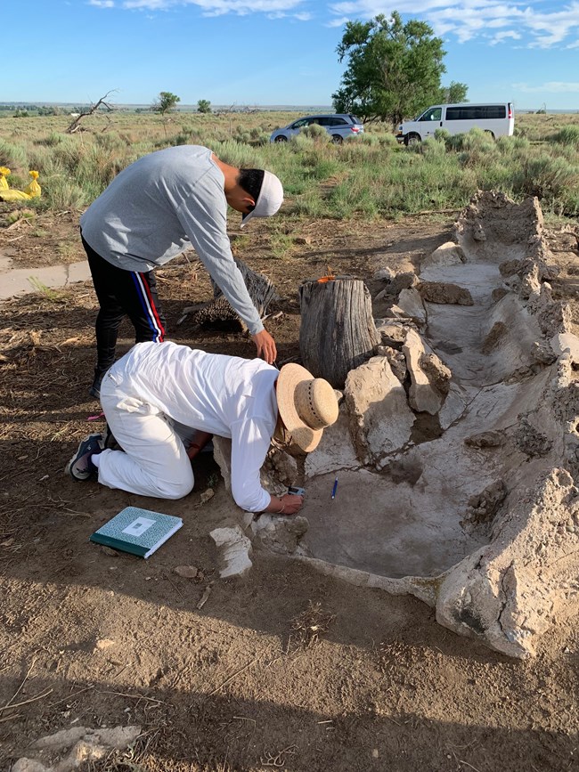 Dr. Clark measuring the drainage hole on the pond/waterfall feature with an Amache descendant High School interns