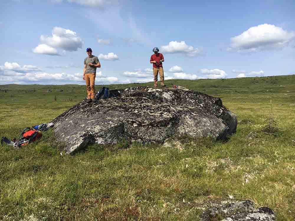 Two men stand on a large boulder.