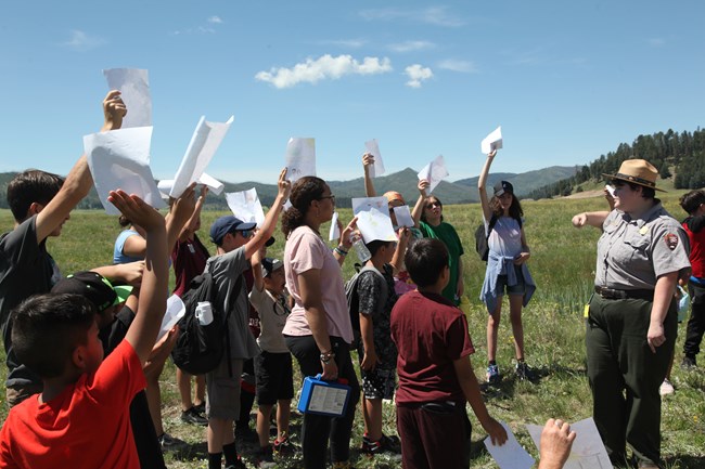 A park ranger facilitates an activity with a group of children.