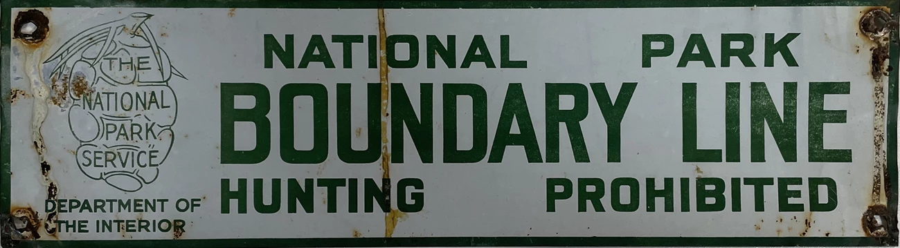 NPS Boundary sign rectangular white sign with green letters and sequoia cone