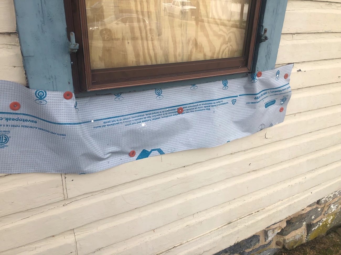 Wooden window frame. The lower section of the window, where the sill ought to be, is covered with weather-proof construction sheeting. Wooden window frame. The lower section of the window, where the sill ought to be, is covered with weather-proof construction sheeting.