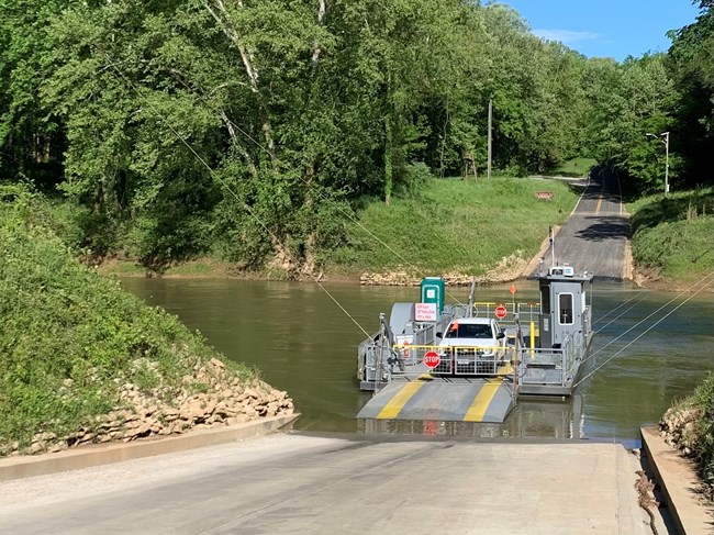 A car is transported across the river on a ferry.