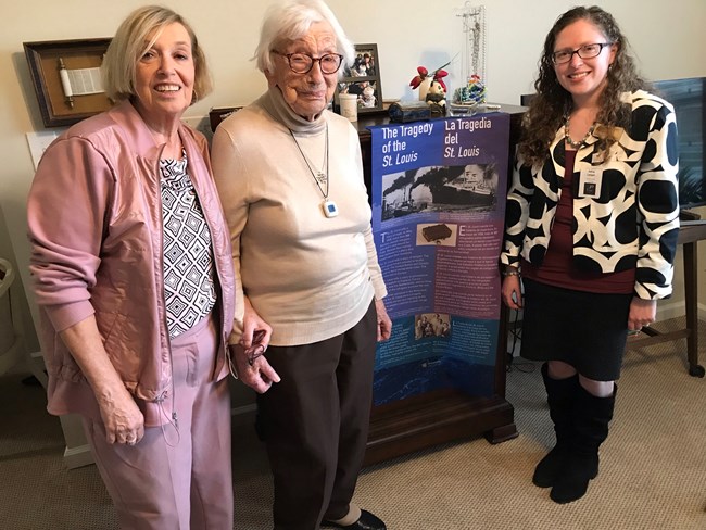 Susan Heinemann Berman and Ruth Simon Heinemann beside a miniature of the first panel of a traveling exhibit about the St. Louis