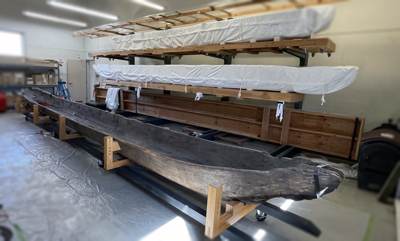 Rehousing canoes in the Nez Perce National Historical Park collections three thirty-foot long, hand-hewn wooden canoes rest on stands, stacked vertically in warehouse