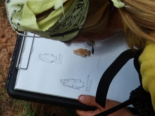 Archaeologist draws field sketch of arrowhead.