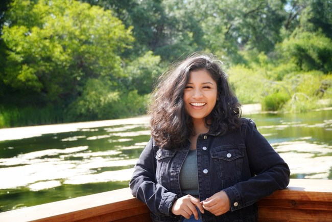 woman stands outside by a river