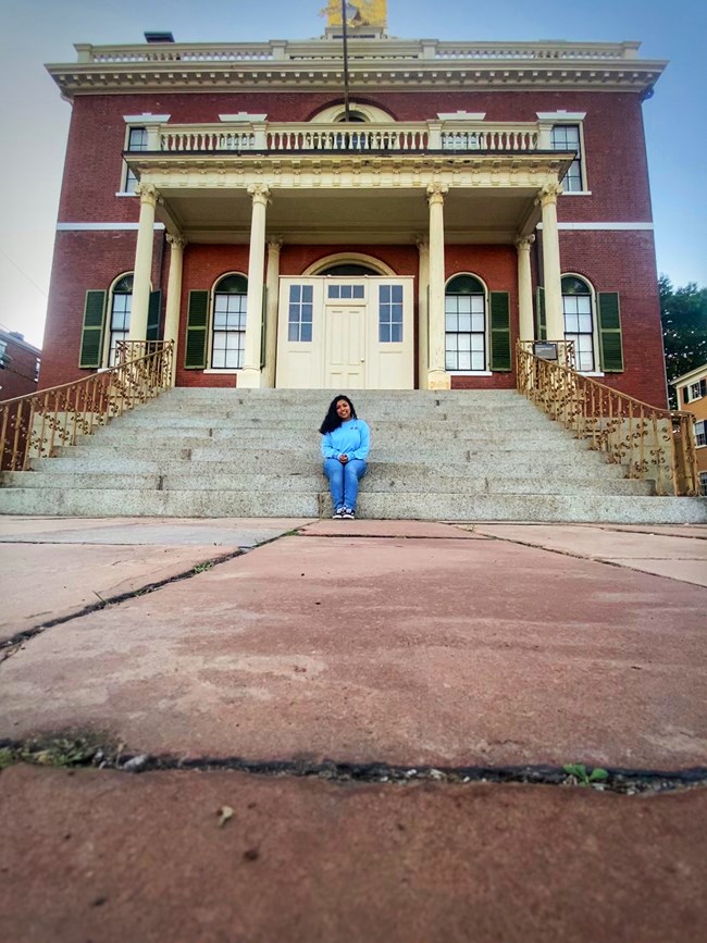 woman sits on steps of brick building